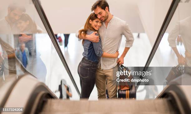 loving couple in an airport on escalator - bleached stock pictures, royalty-free photos & images