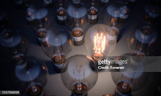 lampadina luminosa incandescente che si distingue dalla massa - ispirazione foto e immagini stock