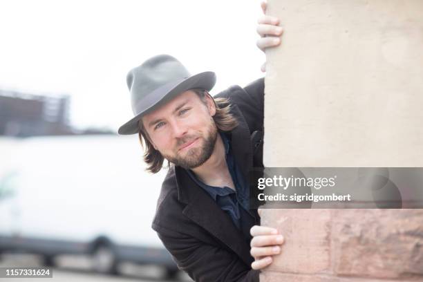 portrait of a man looking round the corner of a building - um die ecke gucken stock-fotos und bilder