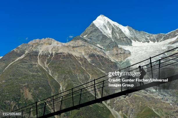 hiker against the weisshorn peak in backlight on the charles kuonen suspension bridge, the worlds longest pedestrian suspension bridge, randa, valais, switzerland - charles bridge stock-fotos und bilder