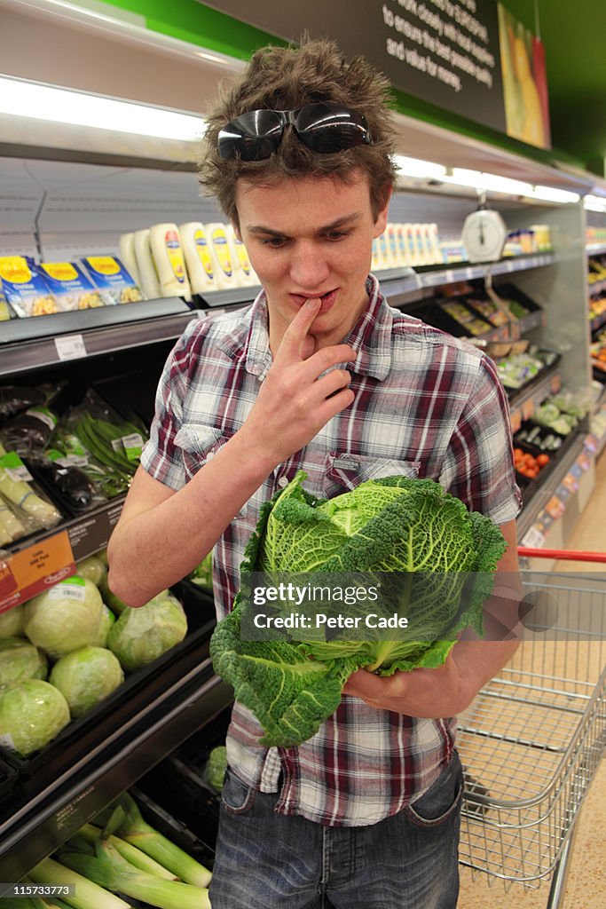 Young man looking confused at cabbage