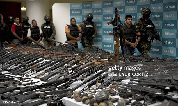 Mexican marines escort five alleged drug traffickers of the Zeta drug cartel in front of an RPG-7 rocket launcher, hand grenades, firearms, cocaine...