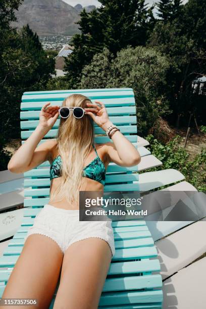 young woman reclining at pool with oddball hair brushed forwards with sunglasses over - sunglasses disguise bildbanksfoton och bilder