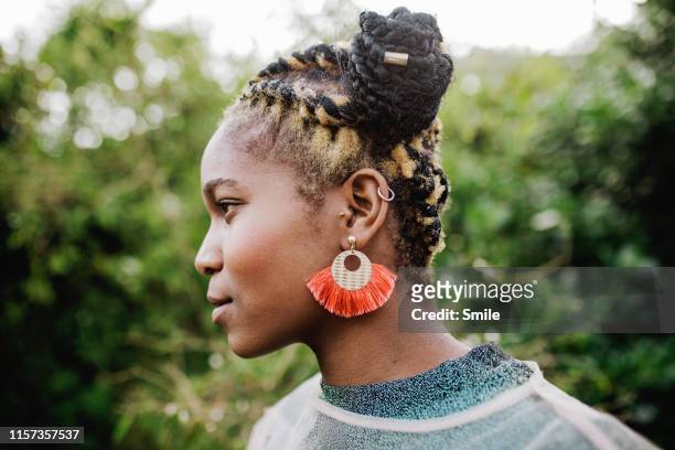 side profile of beautiful young woman with green foliage background - earring fotografías e imágenes de stock