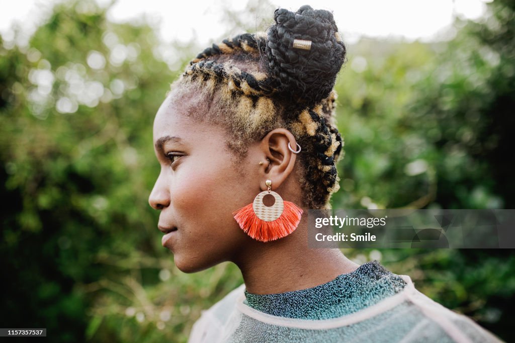 Side profile of beautiful young woman with green foliage background