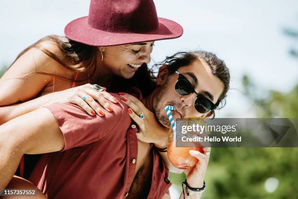 beautiful young woman piggybacked by boyfriend sipping cocktail - cocktail party food stock pictures, royalty-free photos & images