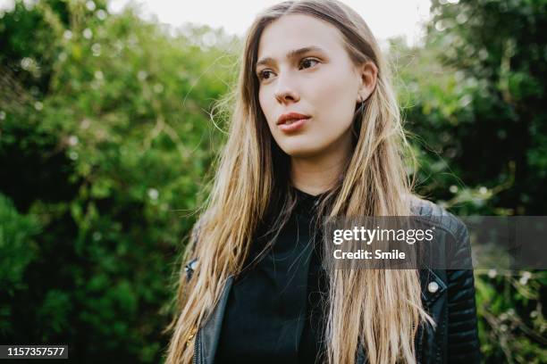 beautiful using woman looking to side with green foliage background - cabelo liso - fotografias e filmes do acervo