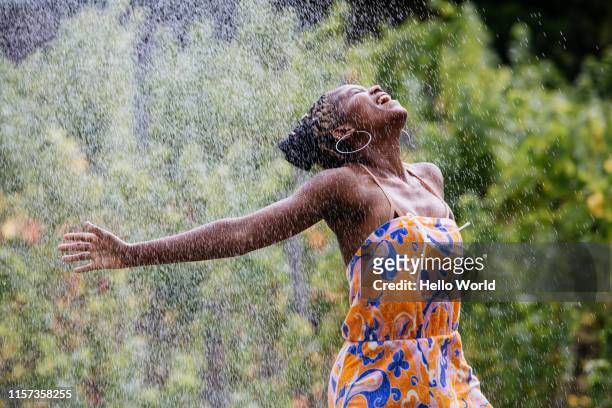 beautiful young woman loving water spray outdoors - beautiful black women in bathing suits stock pictures, royalty-free photos & images