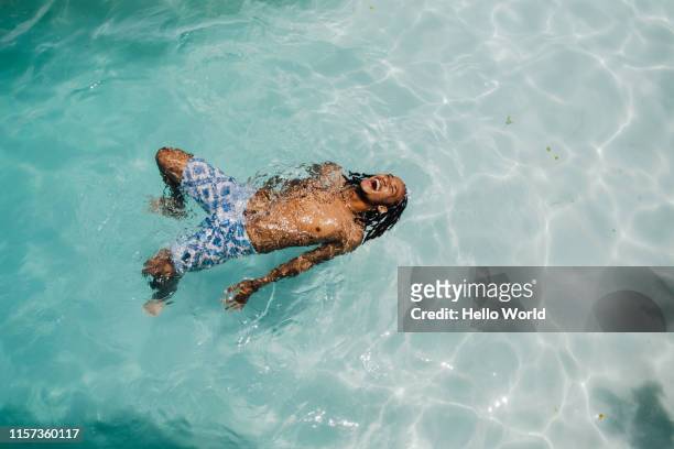 happy young man reclining in crystal clear water - floating on water stock pictures, royalty-free photos & images