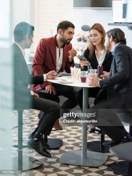 business people using mobile devices during lunch break - workplace canteen lunch stock pictures, royalty-free photos & images