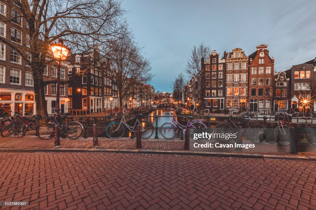 Bicycles standing on bridge on water canal in old town of Amsterdam.