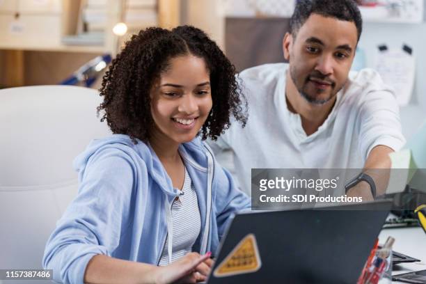 father shows daughter how to find video on laptop - person of colour stock pictures, royalty-free photos & images