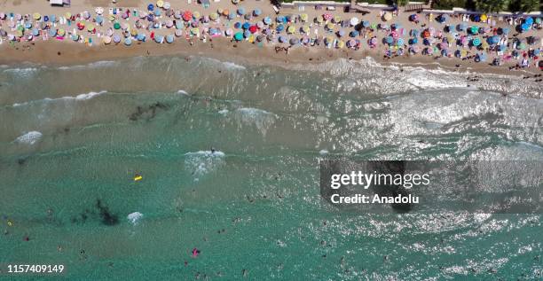 Drone photo shows the aerial view of a beach as people sunbathe under colourful parasols and swim in the sea in Kusadasi district of Aydin, Turkey on...