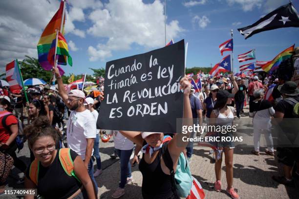 Woman displays a placard reading "When the tyranny is law, the revolution is order" as people take to the Las Americas Highway in San Juan, Puerto...
