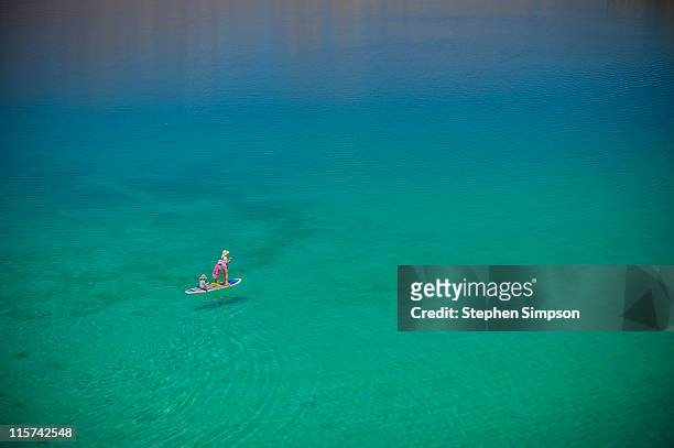 3 children on paddle board, wide blue-green sea - baja california sur stock pictures, royalty-free photos & images