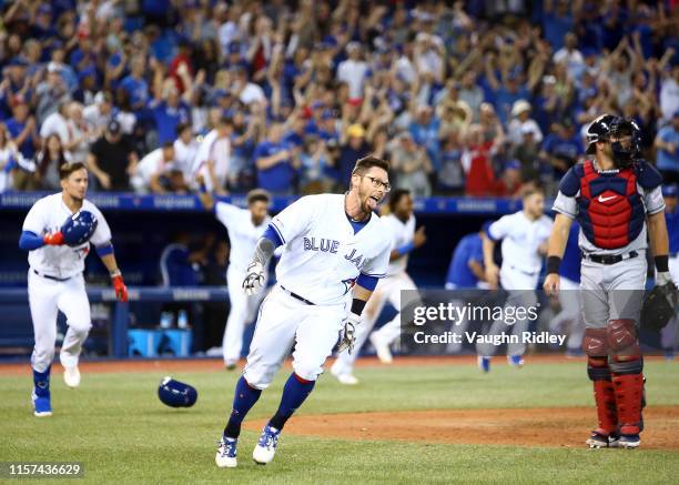 Eric Sogard of the Toronto Blue Jays scores the game winning run on a single by Justin Smoak in the tenth inning during a MLB game against the...