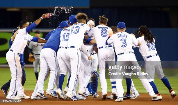 Teammates celebrate with Justin Smoak of the Toronto Blue Jays after he hit a game winning RBI single in the tenth inning during a MLB game against...