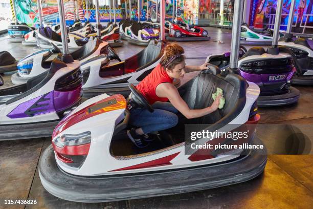 July 2019, Hamburg: Mandy Friedrich, employee, cleans a bumper car on the "Autoscooter Stardust" layout at the Hamburg Summer Cathedral 2019. The...