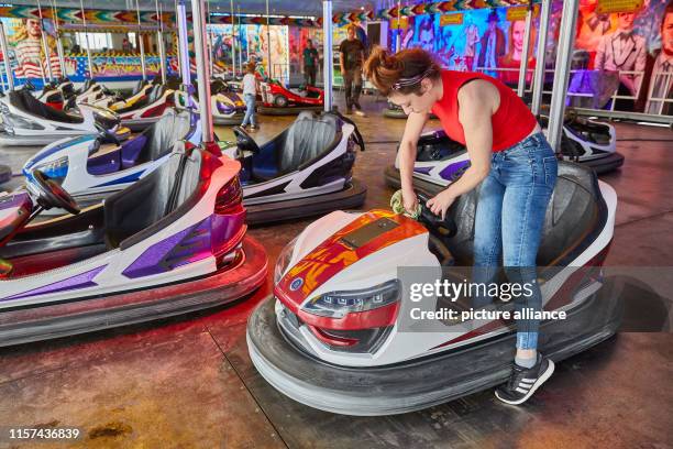 July 2019, Hamburg: Mandy Friedrich, employee, cleans a bumper car on the "Autoscooter Stardust" layout at the Hamburg Summer Cathedral 2019. The...