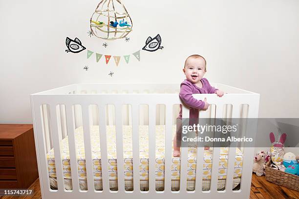 baby in crib surrounded by toys - crib stock pictures, royalty-free photos & images