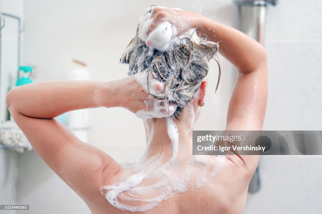 Achteraanzicht van de jonge vrouw die haar haar wast