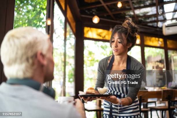 waitress serving customer in a restaurant - serving dish stock pictures, royalty-free photos & images