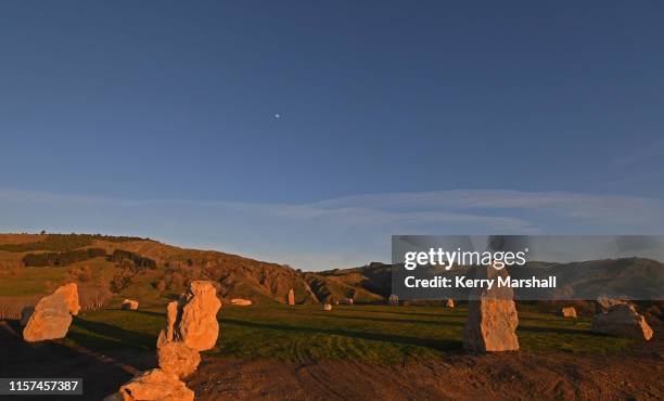 The moon sets as the sun starts to illuminate the stones at the Hakikino Conservation Reserve on June 22, 2019 in Waimarama, New Zealand. The Mātai...