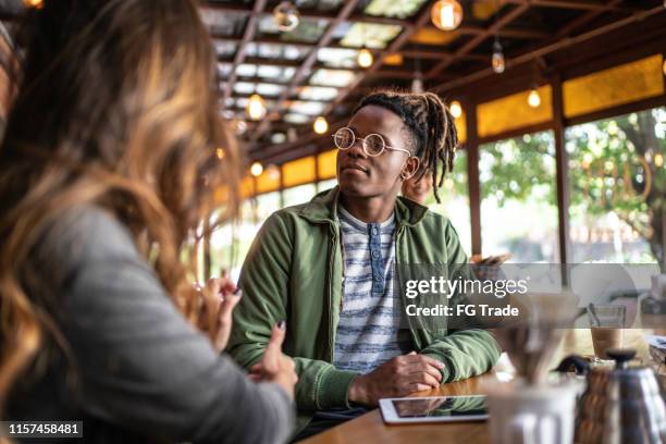 glückliche kellnerin serviert essen zu einer gruppe von freunden in einer cafeteria - hipster coffee shop candid stock-fotos und bilder