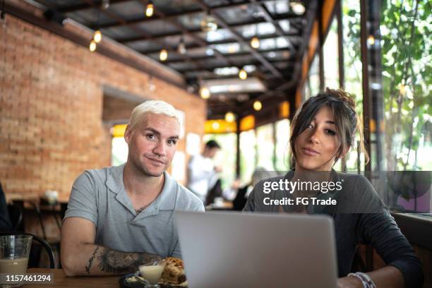 portrait of couple analyzing data using laptop inside a cafeteria - coffee shop display stock pictures, royalty-free photos & images