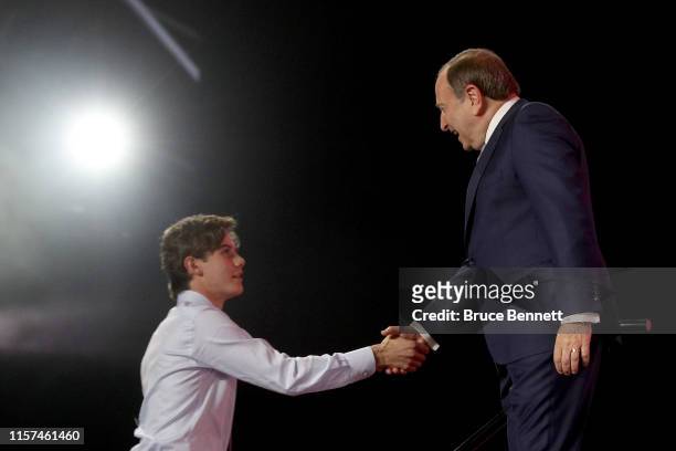 Commissioner Gary Bettman shakes hands with Jack Hughes after being selected first overall by the New Jersey Devils during the first round of the...