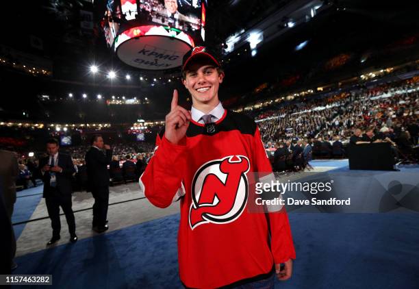 Jack Hughes, first overall pick by the New Jersey Devils, holds up a finger for number one on the draft floor during the first round of the 2019 NHL...