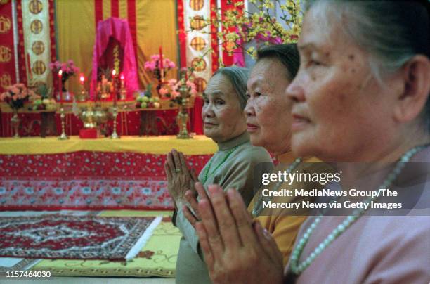Khai Truong, Sau Pham, and Ly Ngoc Anh, all from San Jose, worship at the ancestors altar in the Fiesta Hall at the Santa Clara County Fairgrounds...