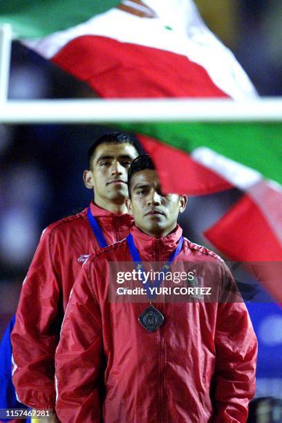 The Mexican flag waves as Mexican athletes Pablo Castano and Teodoro Vega stand with winning medals in San Salvador, El Salvador 02 December 2002....