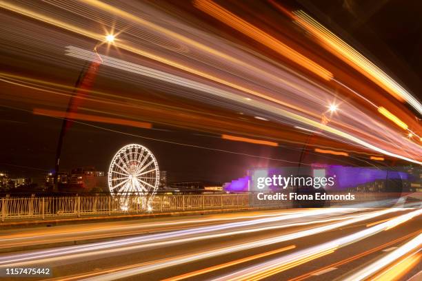 blurred light trails over a bridge with ferris wheel in background - brisbane wheel stock pictures, royalty-free photos & images