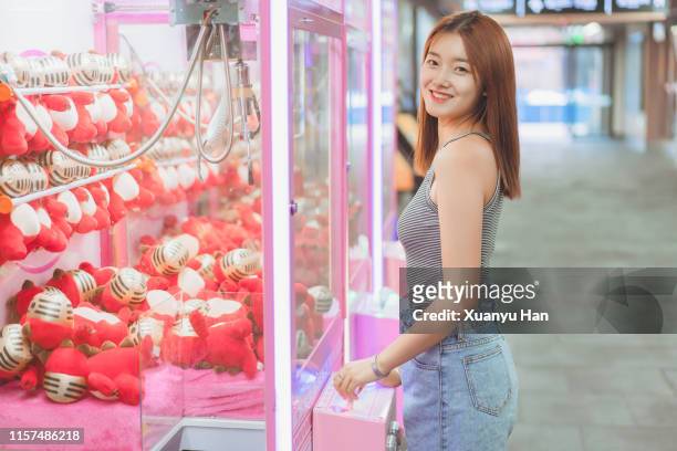 young woman playing arcade game - claw machine stockfoto's en -beelden