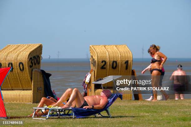 Man takes a sunbath on July 24, 2019 close to the North Sea beach in Wremen, northwestern Germany, where temperatures reached 34 degrees Celsius....