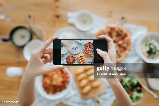 mano della donna che scatta foto di cibo sul tavolo con lo smartphone durante la festa con gli amici - blog foto e immagini stock