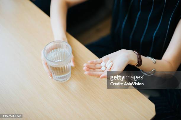 close up of woman holding a glass of water and medication in her hand - diabetes pills stock pictures, royalty-free photos & images
