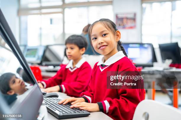 smiling schoolgirl learning computer in lab - middle childhood stock pictures, royalty-free photos & images