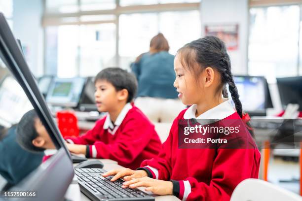 cute schoolgirl learning computer by friend in lab - asian students classroom computer stock pictures, royalty-free photos & images