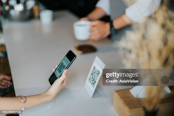 woman's hand holding smartphone, scanning barcode for contactless payment in the cafe - mobile payment stock pictures, royalty-free photos & images