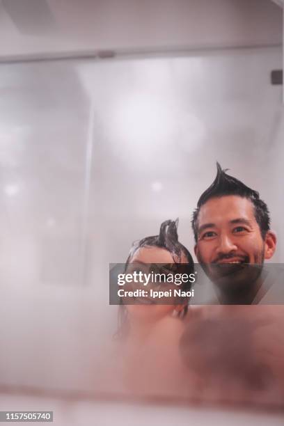 father and child smiling at mirror in bathroom - mirror steam stockfoto's en -beelden