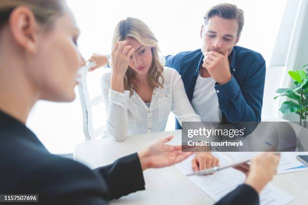 real estate agent with couple looking through documents. - unhappy customer stock pictures, royalty-free photos & images