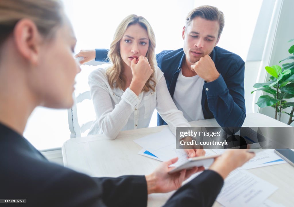 Real estate agent with couple looking through documents.