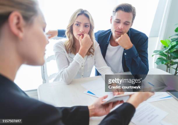 real estate agent with couple looking through documents. - suspicion stock pictures, royalty-free photos & images