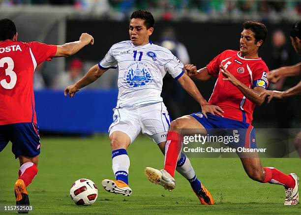 El Salvador's Rodolfo Zelaya dribbles the ball toward the goal as Costa Rica's Jhonny Acosta and Celso Borges apply defensive pressure during...