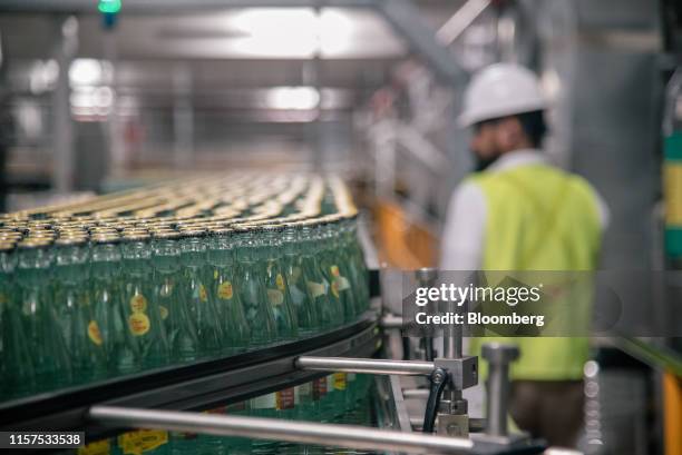 Bottles of Topo Chico mineral water move along a conveyor belt at the Arca Continental SAB production facility in Monterrey, Nuevo Leon state,...