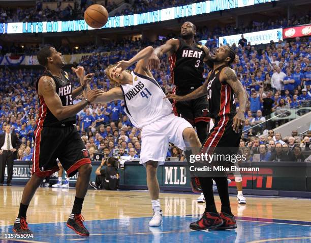 Dirk Nowitzki of the Dallas Mavericks loses the ball as he drives against Mario Chalmers, Dwyae Wade and Udonis Haslem of the Miami Heat in the...