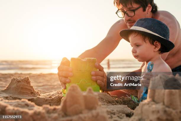 familie spielt am strand und baut sandburg in den sommerferien - kind sandburg stock-fotos und bilder