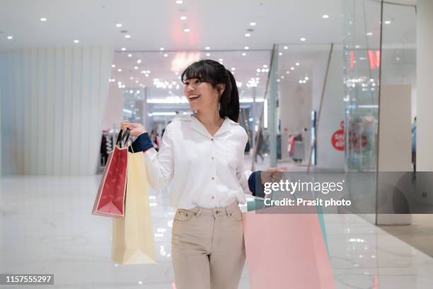 asian woman shopper with paper bags standing in the mall. - shopping mall foto e immagini stock